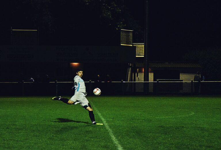 person kicks soccer ball in field